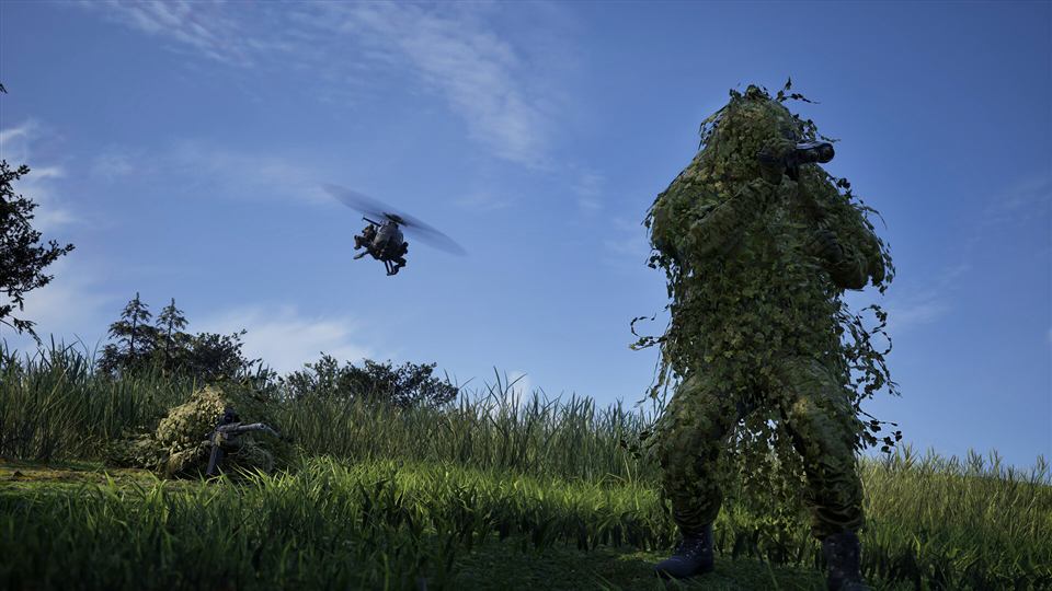 A sniper in a ghillie suit in long grass